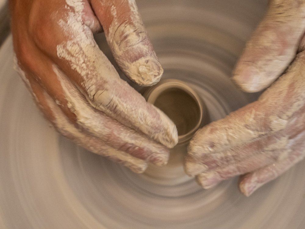 Hands centering clay on a pottery wheel